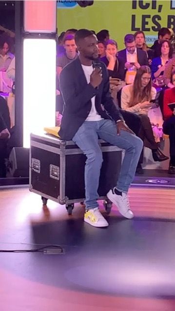 Axel Loupeda assis sur un flight case, sur la scène circulaire de l'Ampli, devant le public