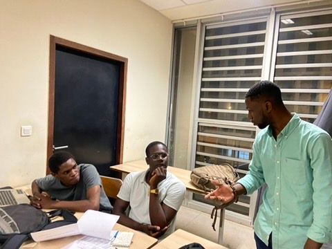 Axel Loupeda échange avec deux jeunes entrepreneurs penchés sur leurs dossiers, dans une salle de travail